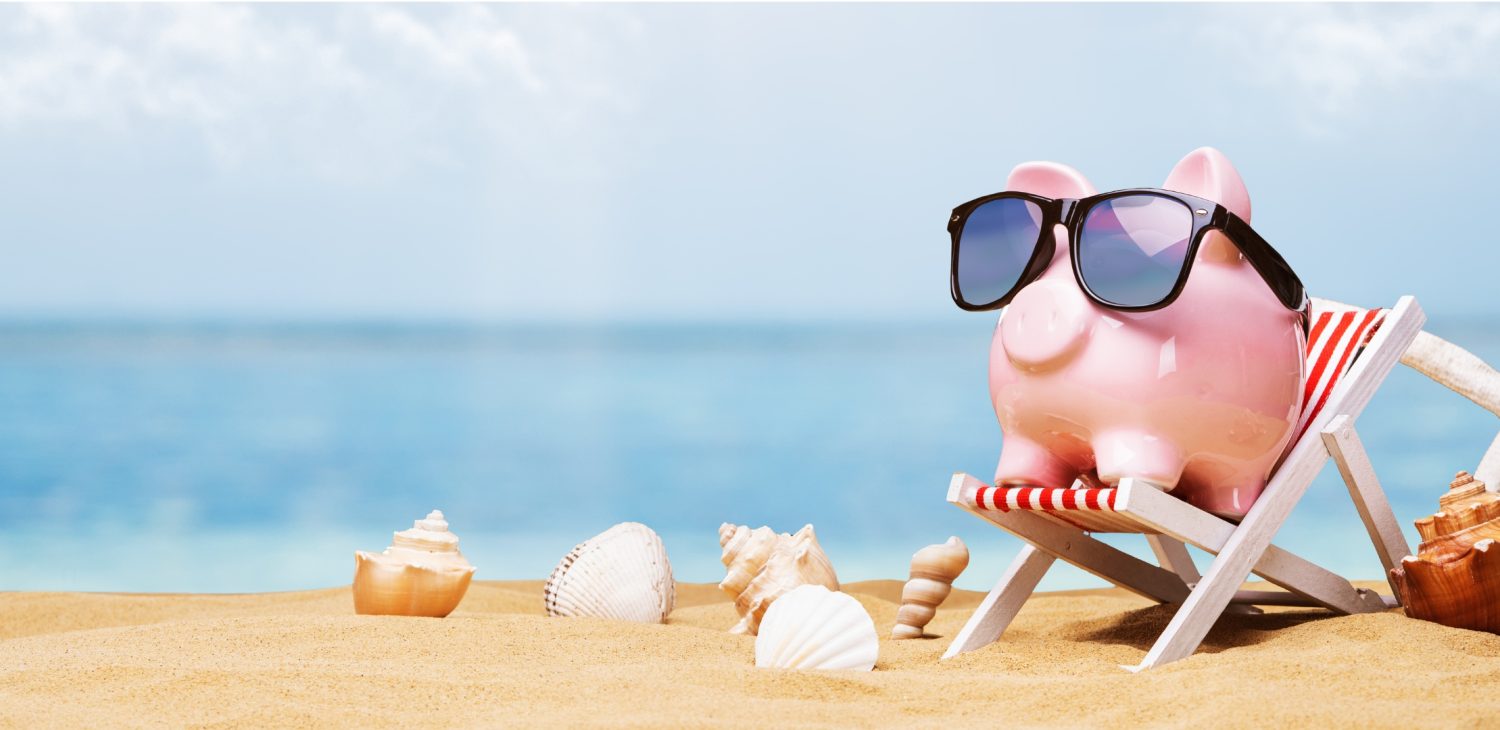 A pink piggy bank relaxing in a deck chair on a sunny beach